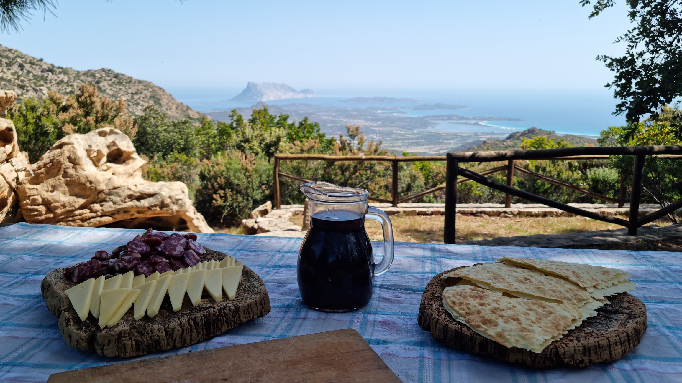 Panorama da Paladimonti con aperitivo tipico sardo composto da vino Cannonau, pane carasau, salsiccia secca e formaggio di pecora